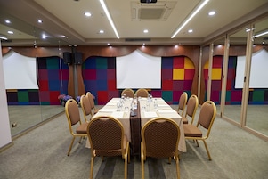 Una sala de conferencias con una larga mesa, sillas, un proyector y una pared colorida.
