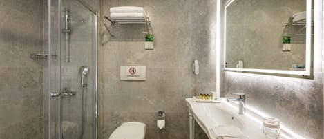 A modern bathroom with a glass-enclosed shower, a white toilet, a sink with a mirror, and a towel rack.