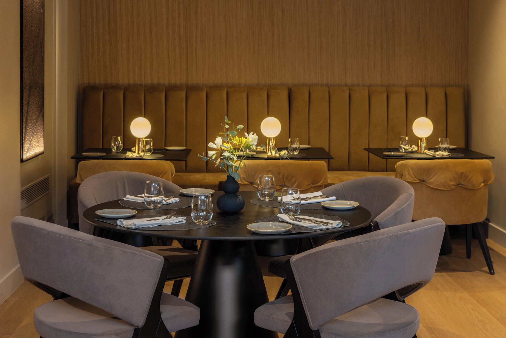 A dining area with round tables, chairs, and a wooden panel wall.