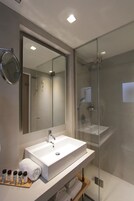 Un bagno moderno con uno specchio grande, un lavandino bianco e una cabina doccia in vetro.