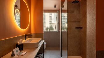 Une salle de bain moderne avec un grand miroir, un lavabo et une douche.