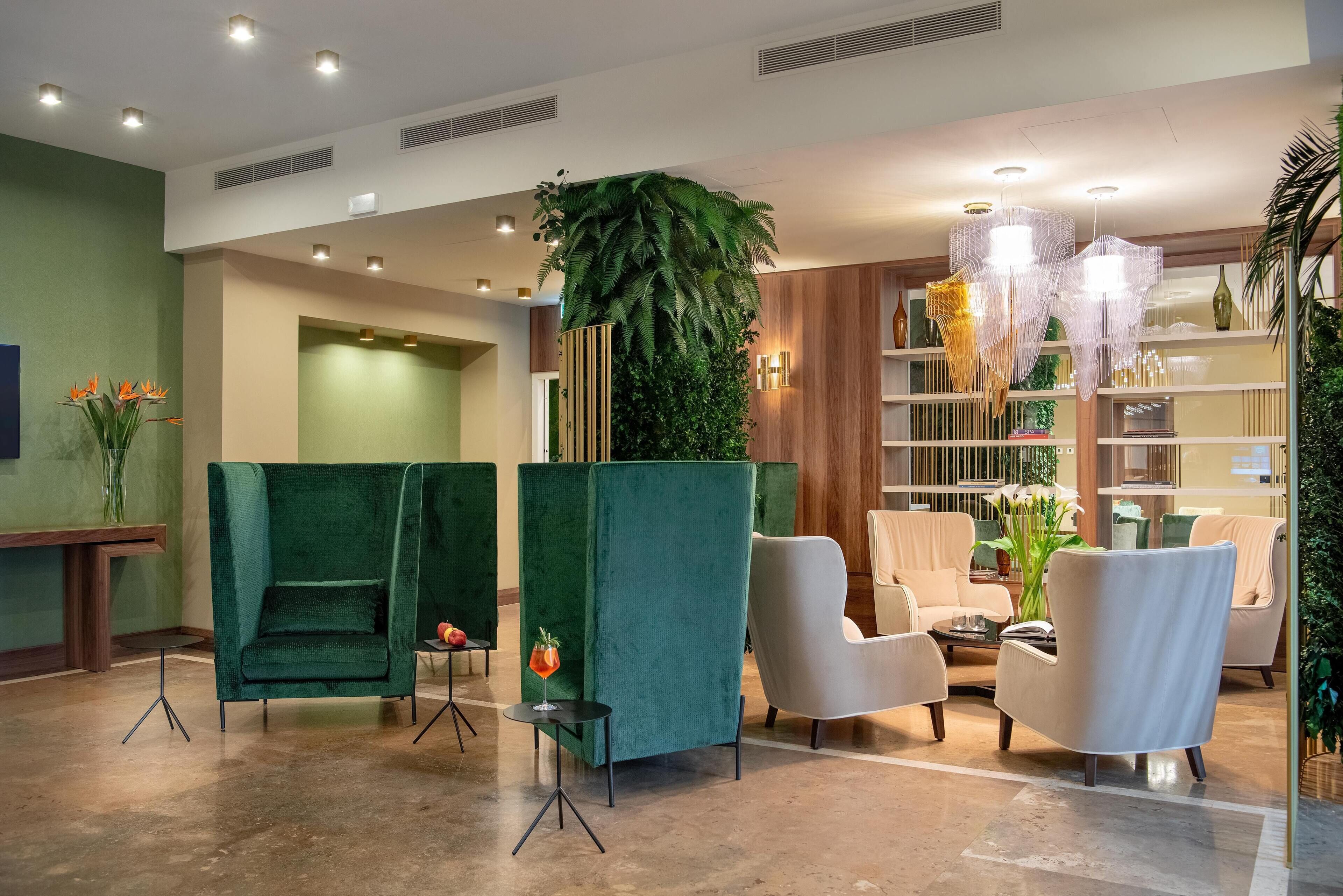A lobby with green partitions, a reception desk, and seating areas with a large plant and decorative lighting.