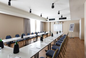 Kokoushuone, jossa on pitkä pöytä, tuoleja, projektorikangas ja valkotaulu.