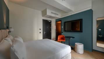 A modern hotel room with a large bed, a small table, a chair, and a television.