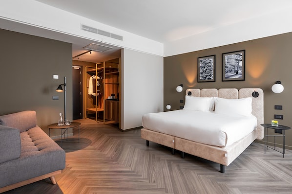 Een moderne hotelkamer met een groot bed, een zithoek en een inloopkast.