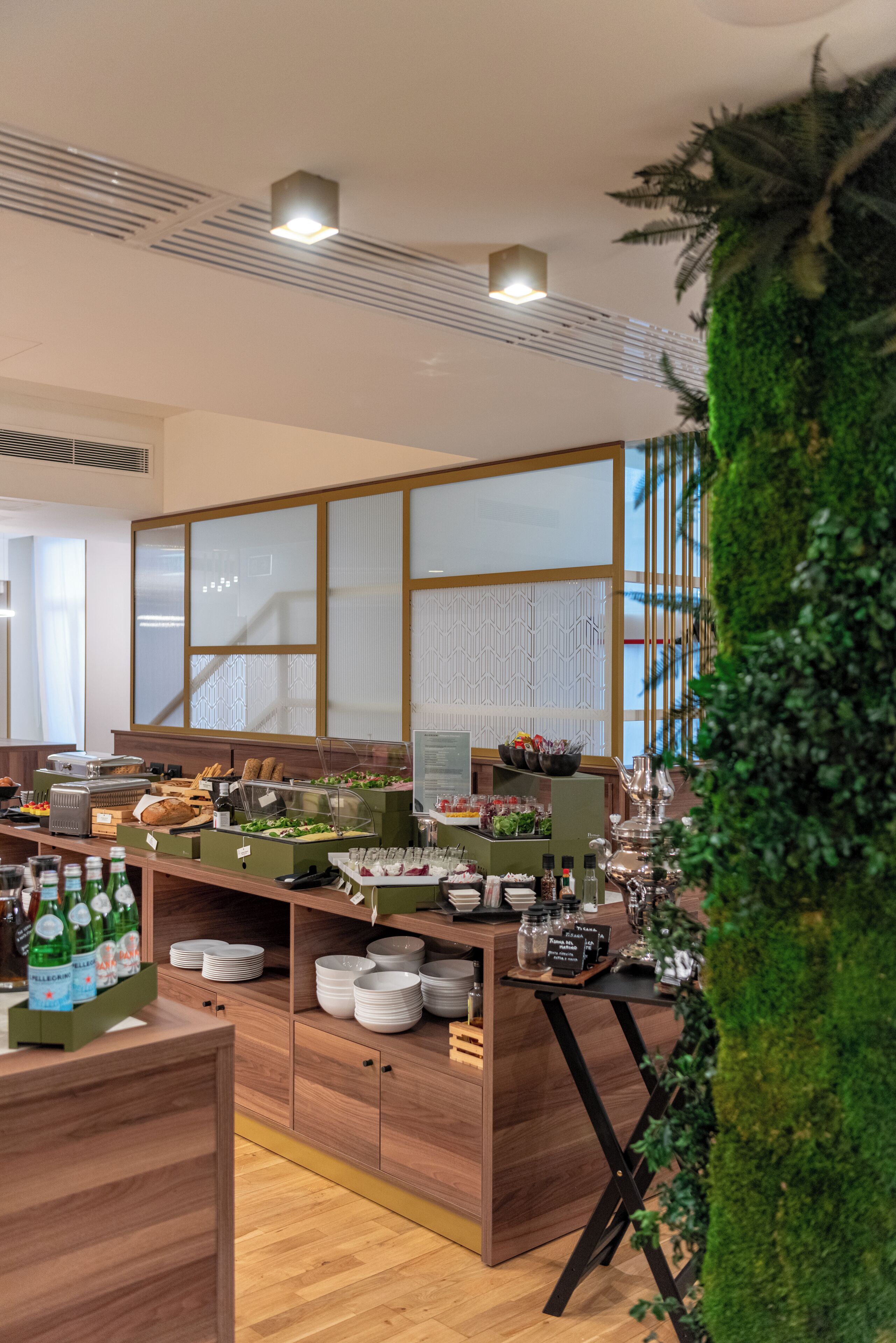 A modern kitchen with wooden cabinets, a buffet setup, and a green wall feature.