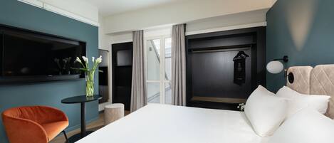 Una habitación de hotel moderna con una cama grande, una mesita redonda pequeña, una silla y un televisor.
