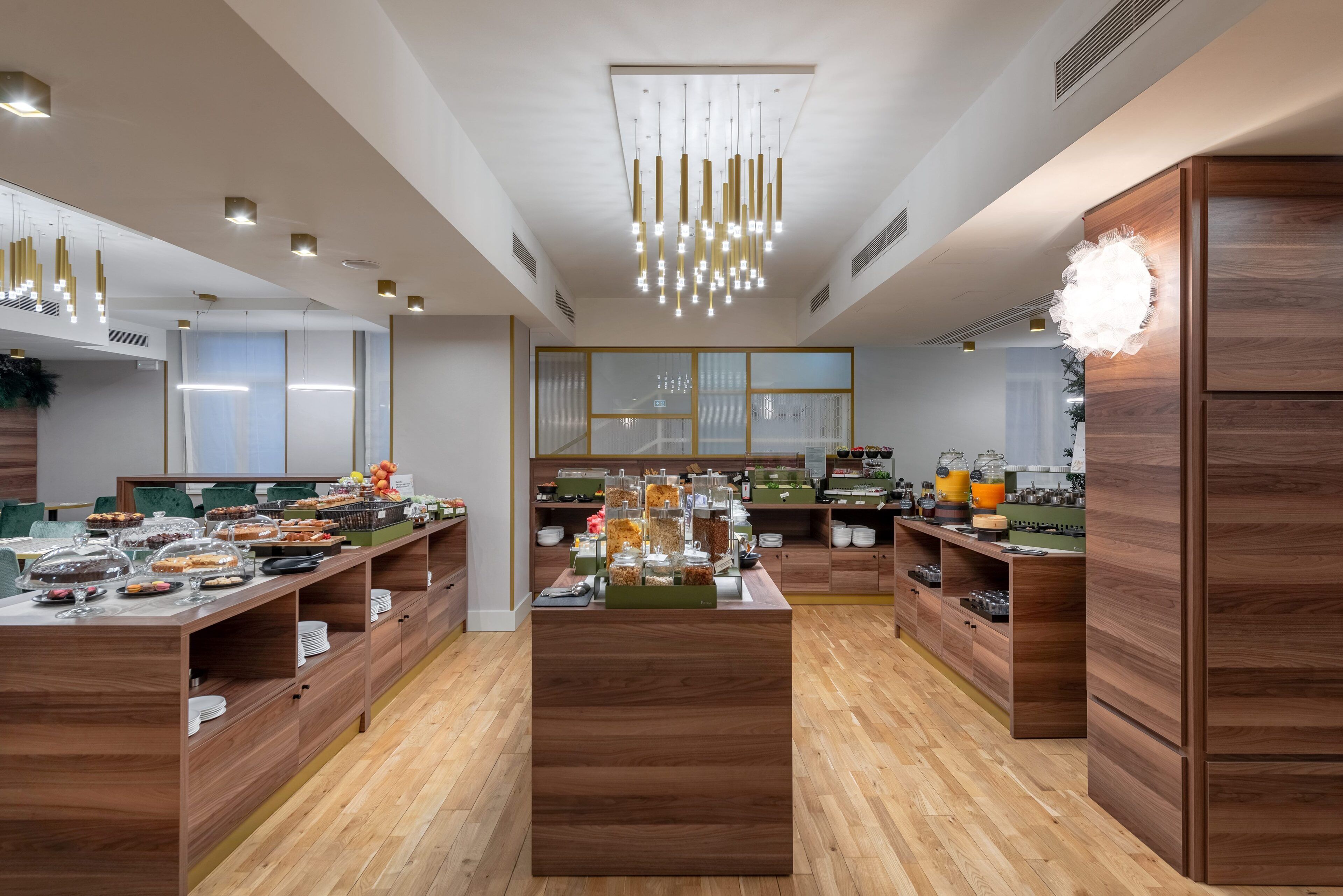 A modern hotel lobby with wooden furniture, a central buffet, and pendant lighting.