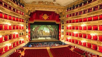 Un magnifique théâtre doté de plusieurs balcons, de sièges rouges et de décorations dorées élaborées.