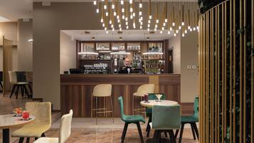 Zona de bar con barra, taburetes y una variedad de botellas y vasos.