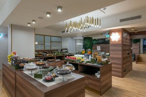 Een moderne keuken met houten kastjes, een centraal eiland met diverse etenswaren, en een hangende lamp.
