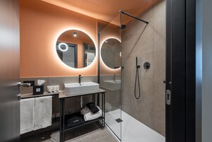 A modern bathroom with a glass-enclosed shower, a vanity with a sink, and two illuminated mirrors.