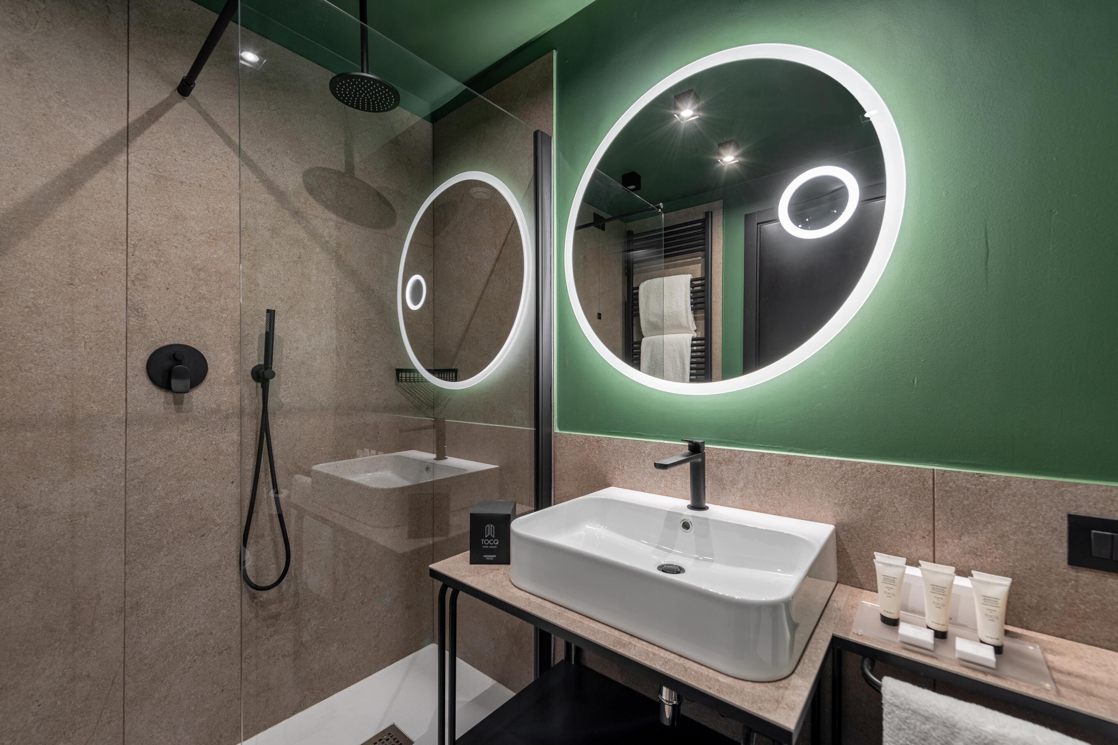Une salle de bain moderne avec un grand miroir, un lavabo et une douche.