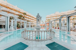 Um hotel luxuoso com piscina central, várias varandas e arquitetura clássica.