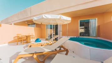 Un espace piscine aménagé sur le toit, avec des chaises longues, une table et un parasol.