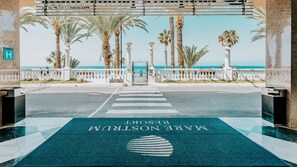 A hotel entrance with a view of the beach and palm trees. - Cleopatra Palace Hotel (Arona)