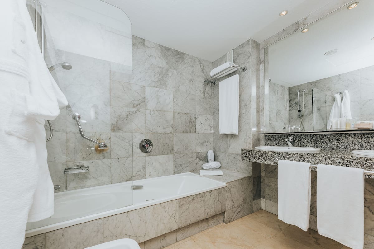 A modern bathroom with a bathtub, shower, and two sinks.