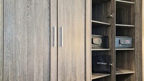 A wooden wardrobe with a hair dryer and a small electronic device. - Astor Court Hotel (London)