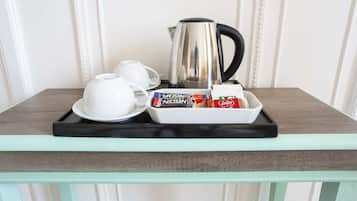 Un plateau avec une cafetière, deux tasses et une boîte de collations, posé sur une table.