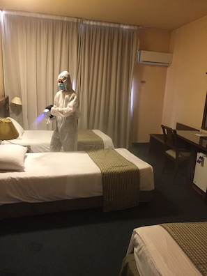 Een hotelkamer met twee bedden, een bureau en een airconditioning.