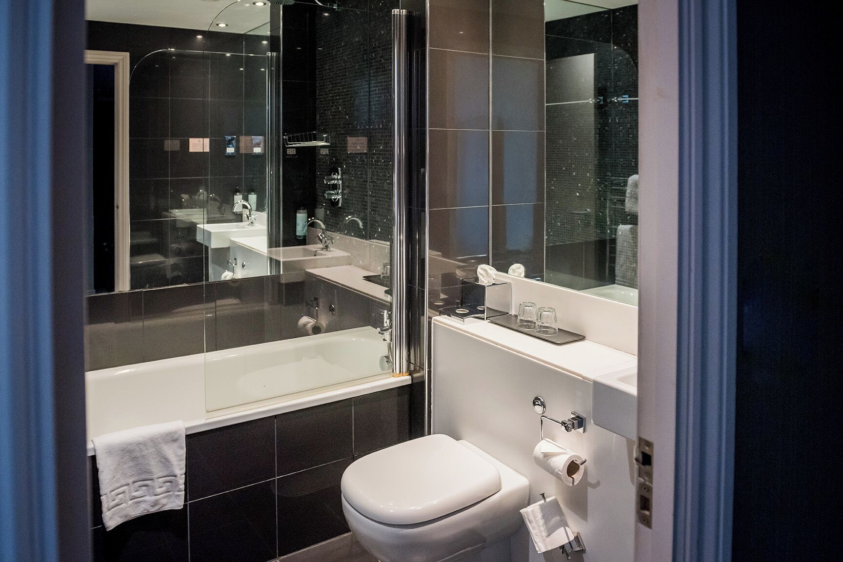 Een moderne badkamer met een douchecabine van glas, een wit toilet en een wastafel met spiegel.