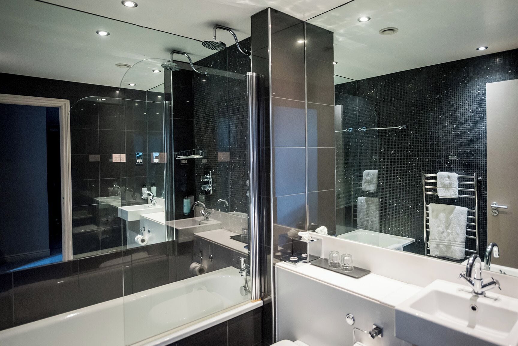 A modern bathroom with a glass-enclosed shower, two sinks, and a large mirror.