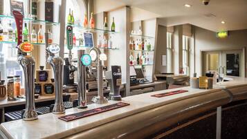 A bar area with multiple taps, including brands like CAMDEN and GUINNESS, and a variety of bottles on shelves in the background.