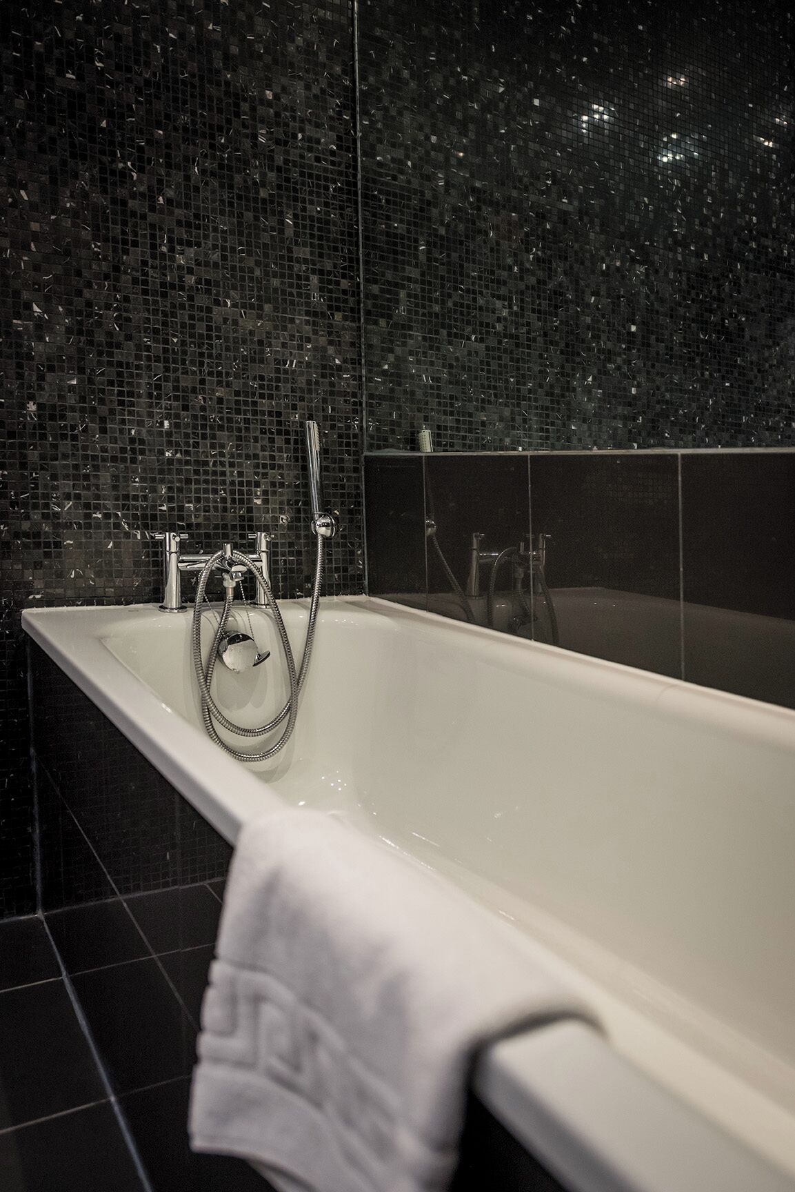 Une salle de bain avec une baignoire, une douche et un mur carrelé.