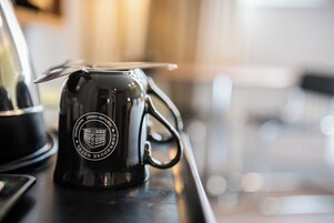 Una taza de café negro con un logotipo sobre una bandeja.