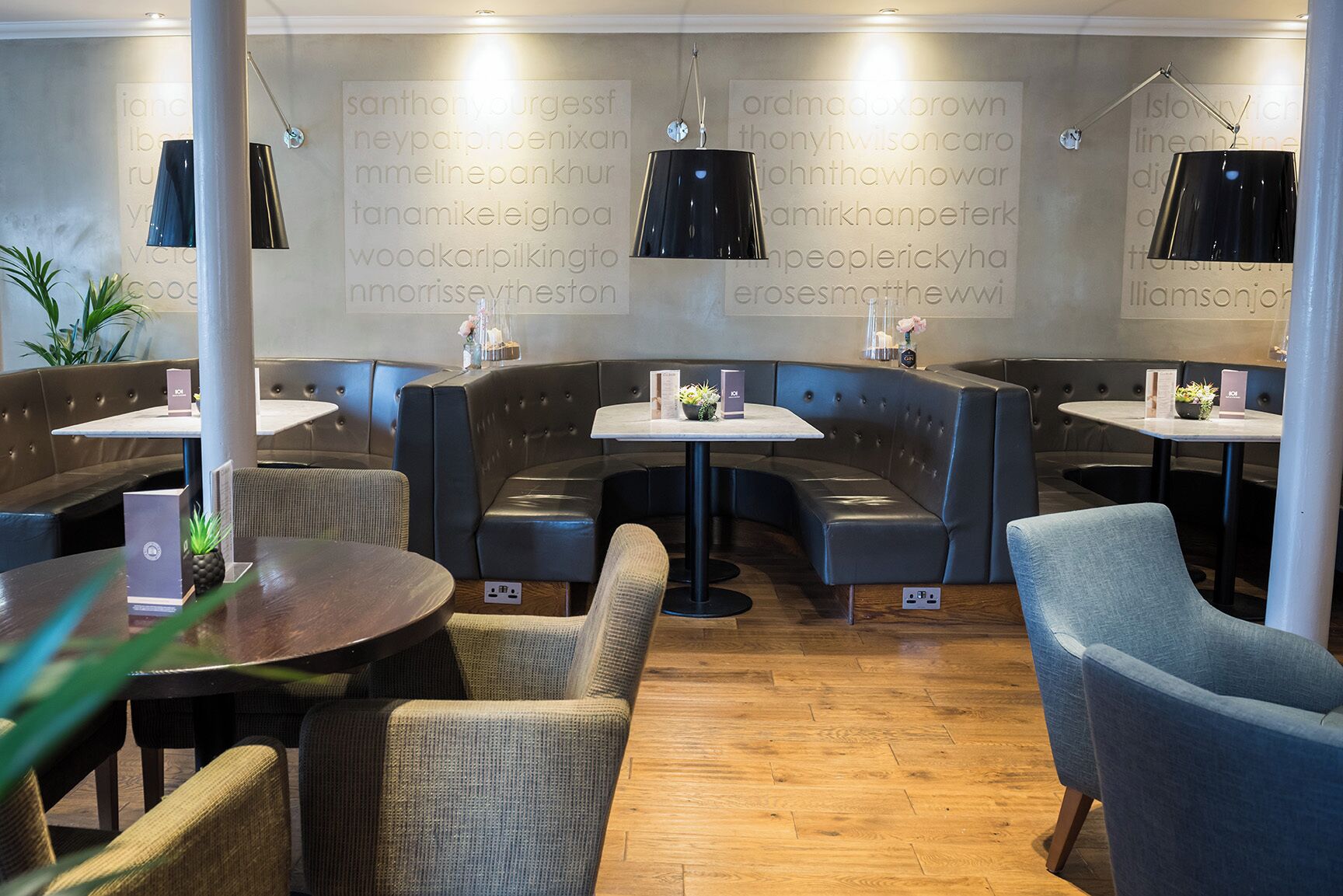 Ein modernes Restaurant mit einer geschwungenen Sitzgruppe, einzelnen Tischen und Pendelleuchten.