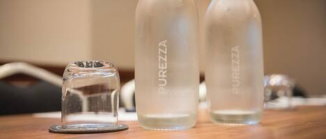 Three glass bottles labeled "PUREZZA" on a wooden surface.
