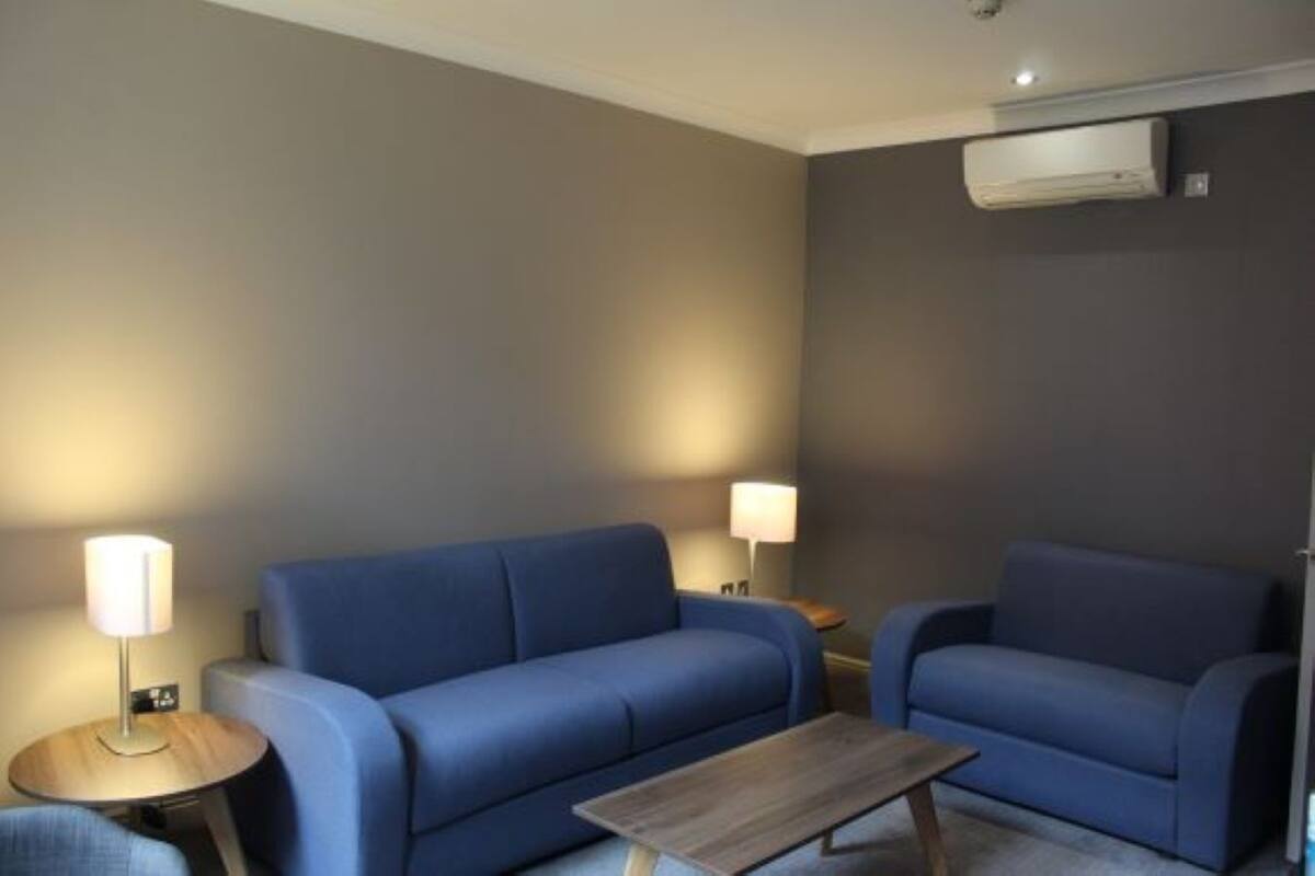 A modern living room with a blue sofa, a wooden coffee table, and two bedside lamps.
