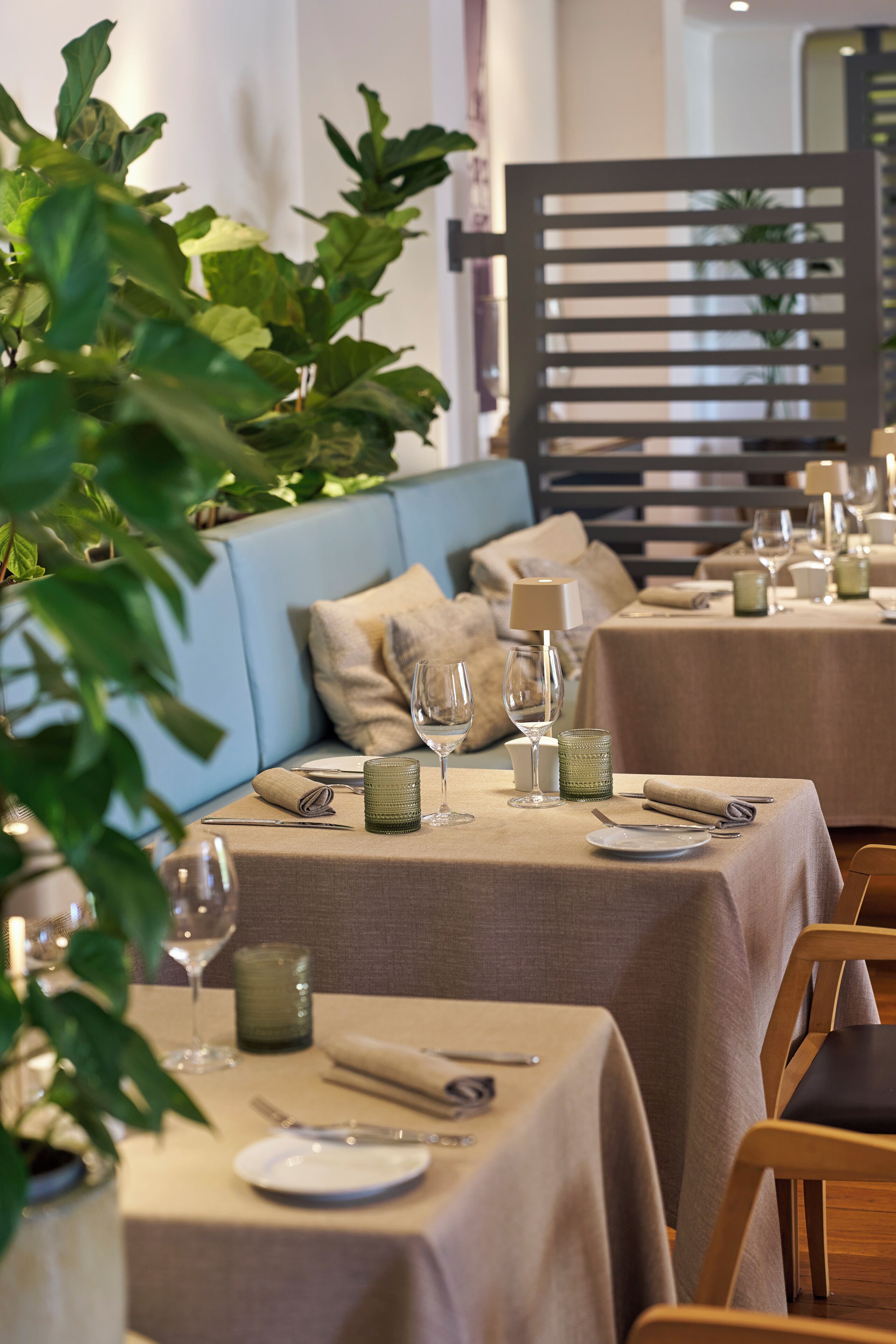 Comedor con mesas dispuestas para dos, con una paleta de colores neutros y decoración moderna.