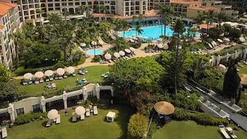 A resort with multiple swimming pools, sun loungers, and palm trees.