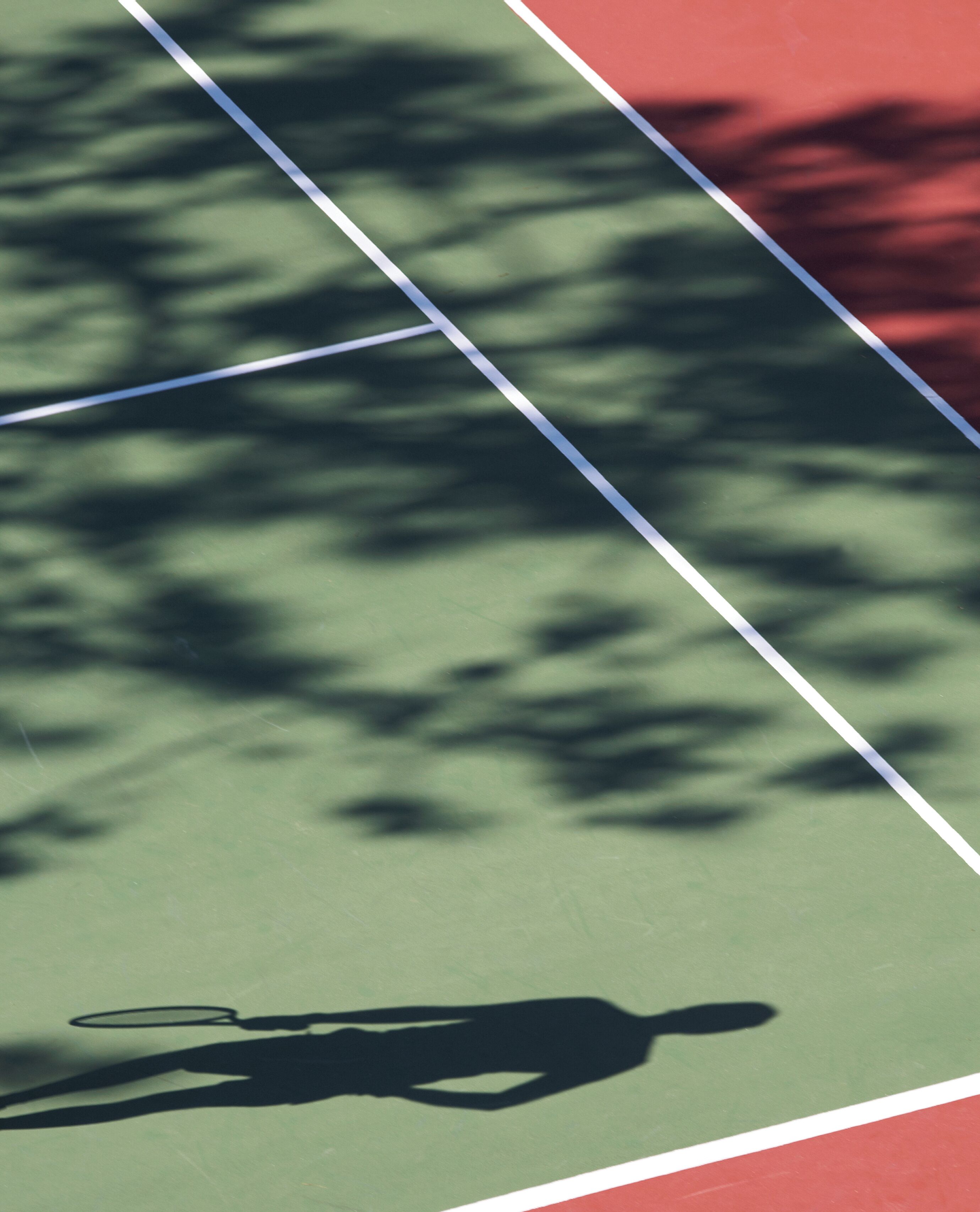 Una cancha de tenis con la sombra de una persona sobre la superficie verde.