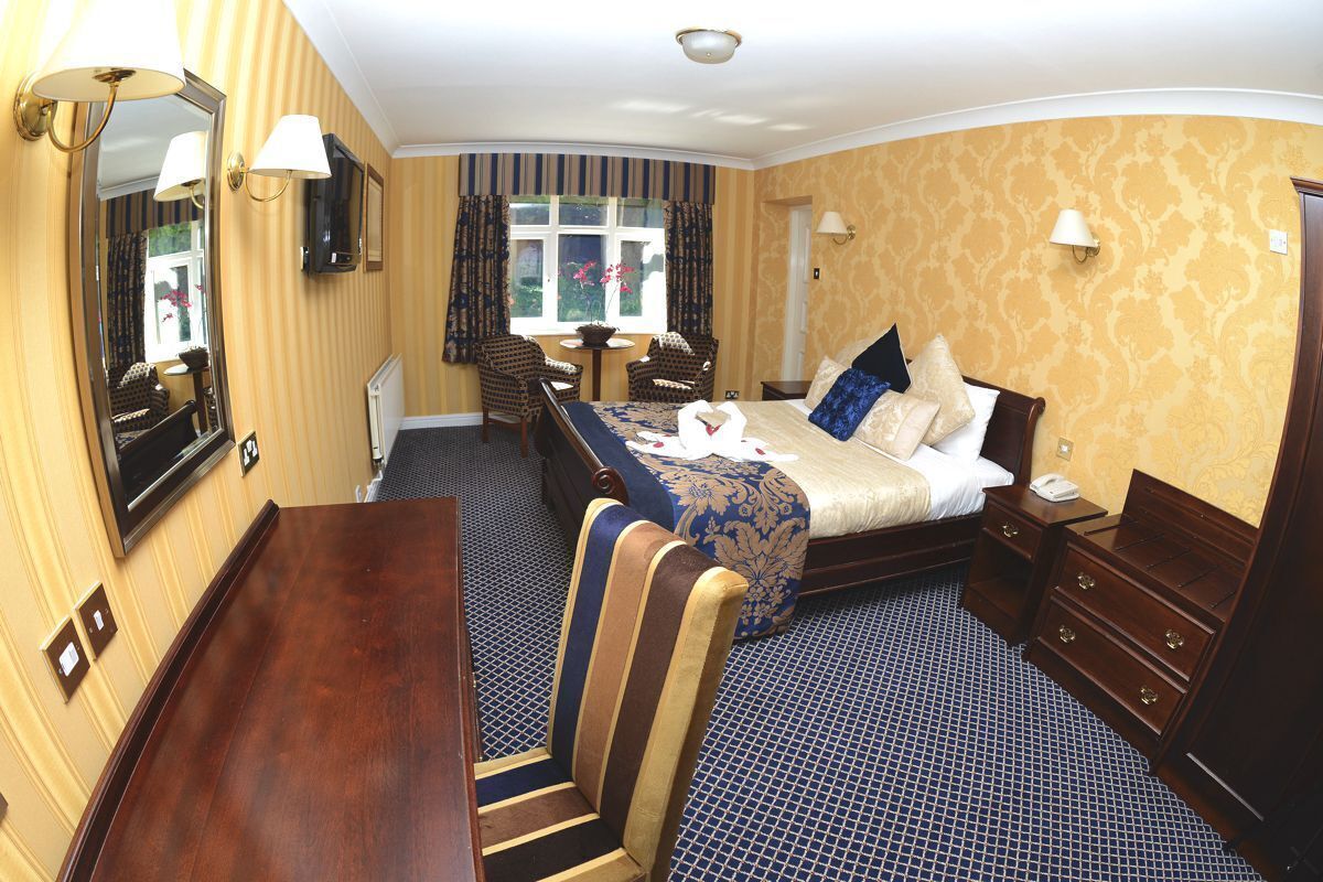 A hotel room with a large bed, a desk, a chair, and a dresser.