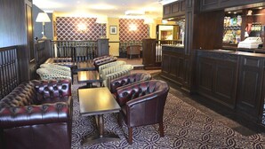 Un hall de hotel con asientos de cuero, una zona de bar y alfombra estampada.