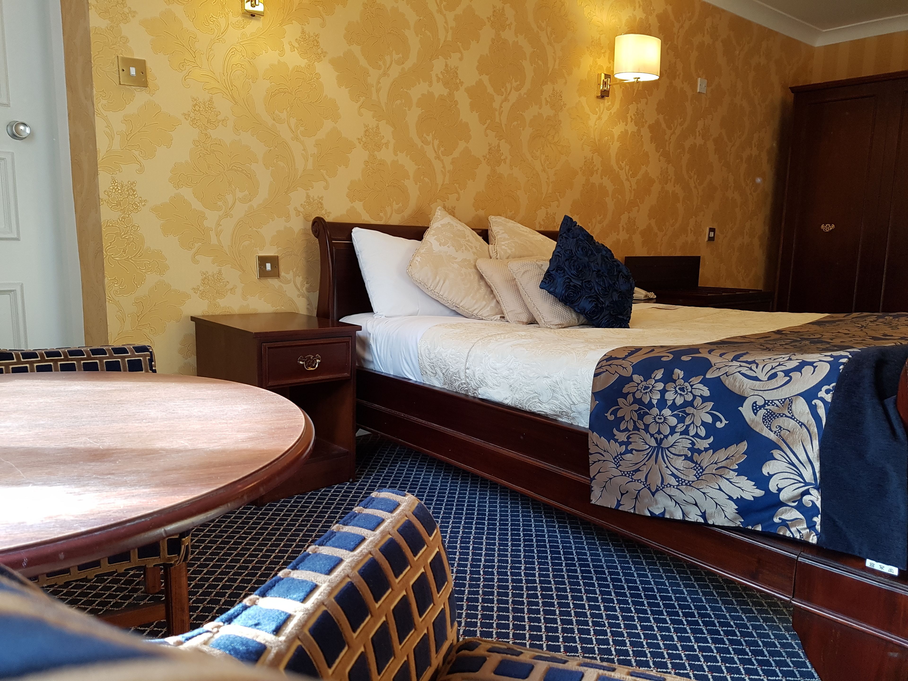 A hotel room with a bed, bedside table, and a round table.