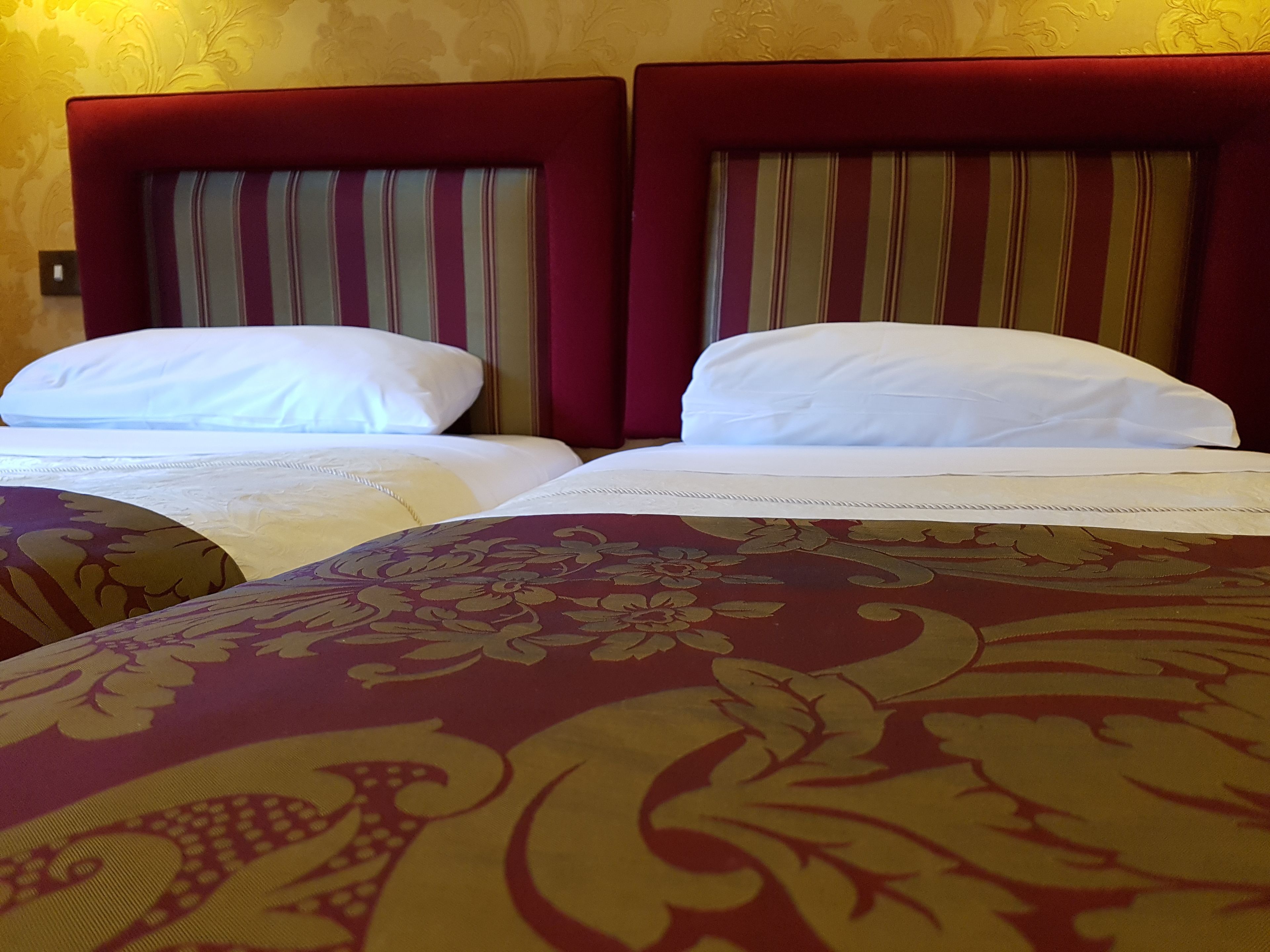 A hotel room with two beds, each with a striped headboard and white bedding.
