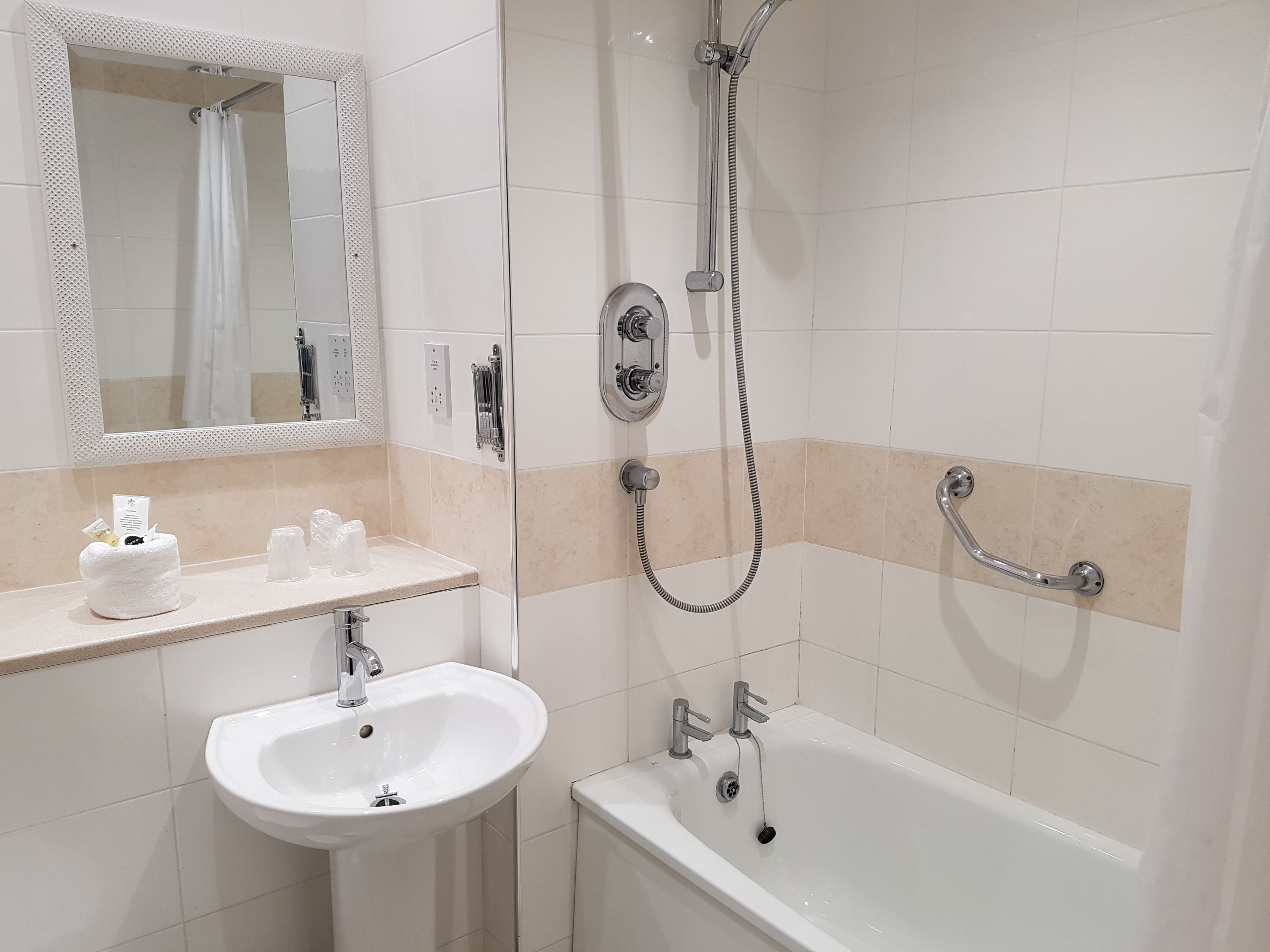 Une salle de bain équipée d’un lavabo, d’un miroir, d’une douche et d’une baignoire.