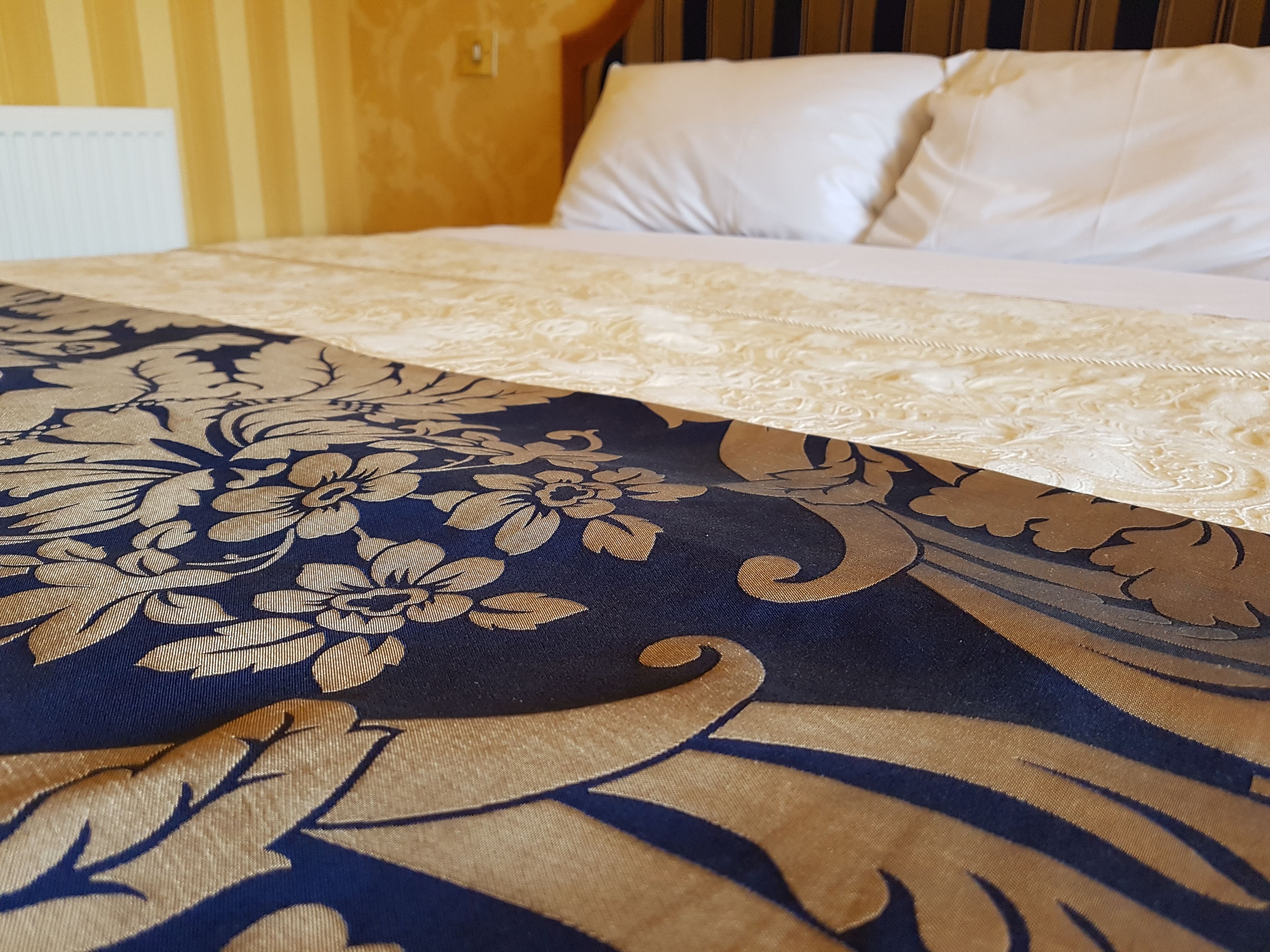 A bed with a floral-patterned bedspread and white pillows.