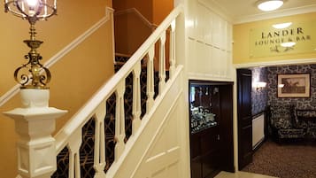 A staircase with white balusters leading to a landing with a sign for 'Lander Lounge & Bar'.