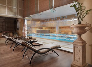 A spa area with sun loungers, a large decorative urn, and a pool with wave patterns. - Divani Apollon Palace & Thalasso (Vari-Voula-Vouliagmeni)
