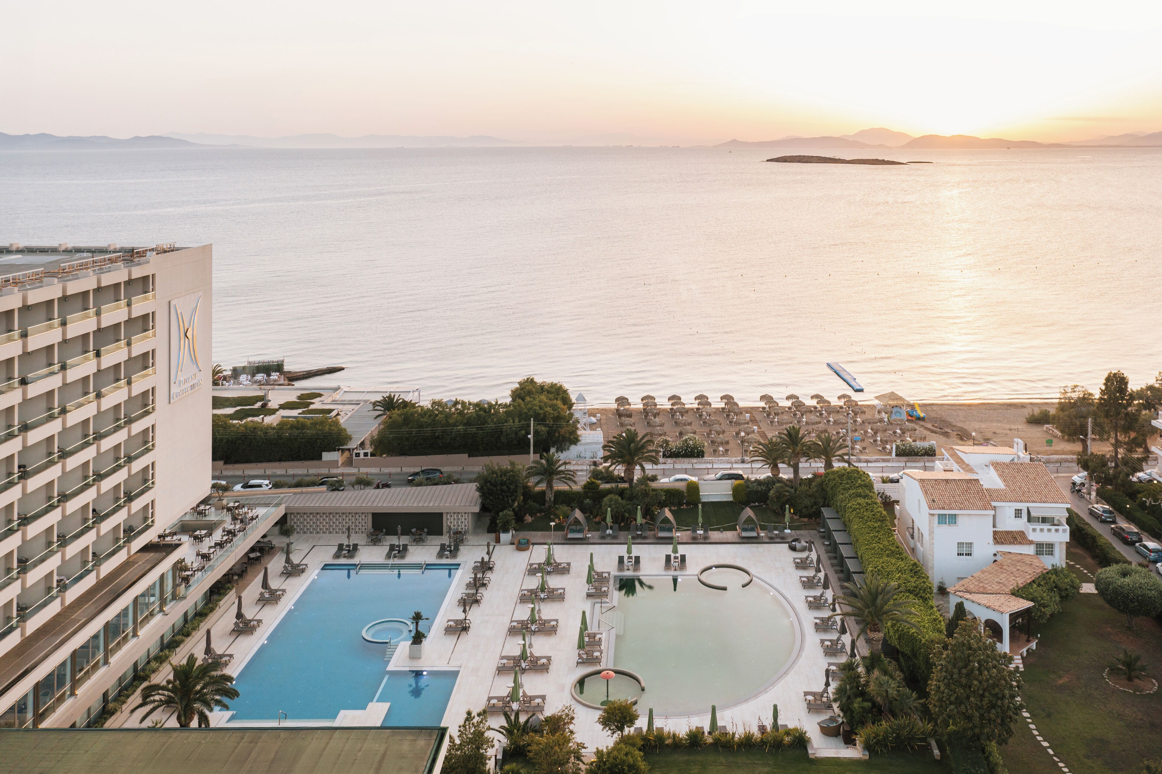Un hotel con piscina, sillas de descanso y vistas al mar.