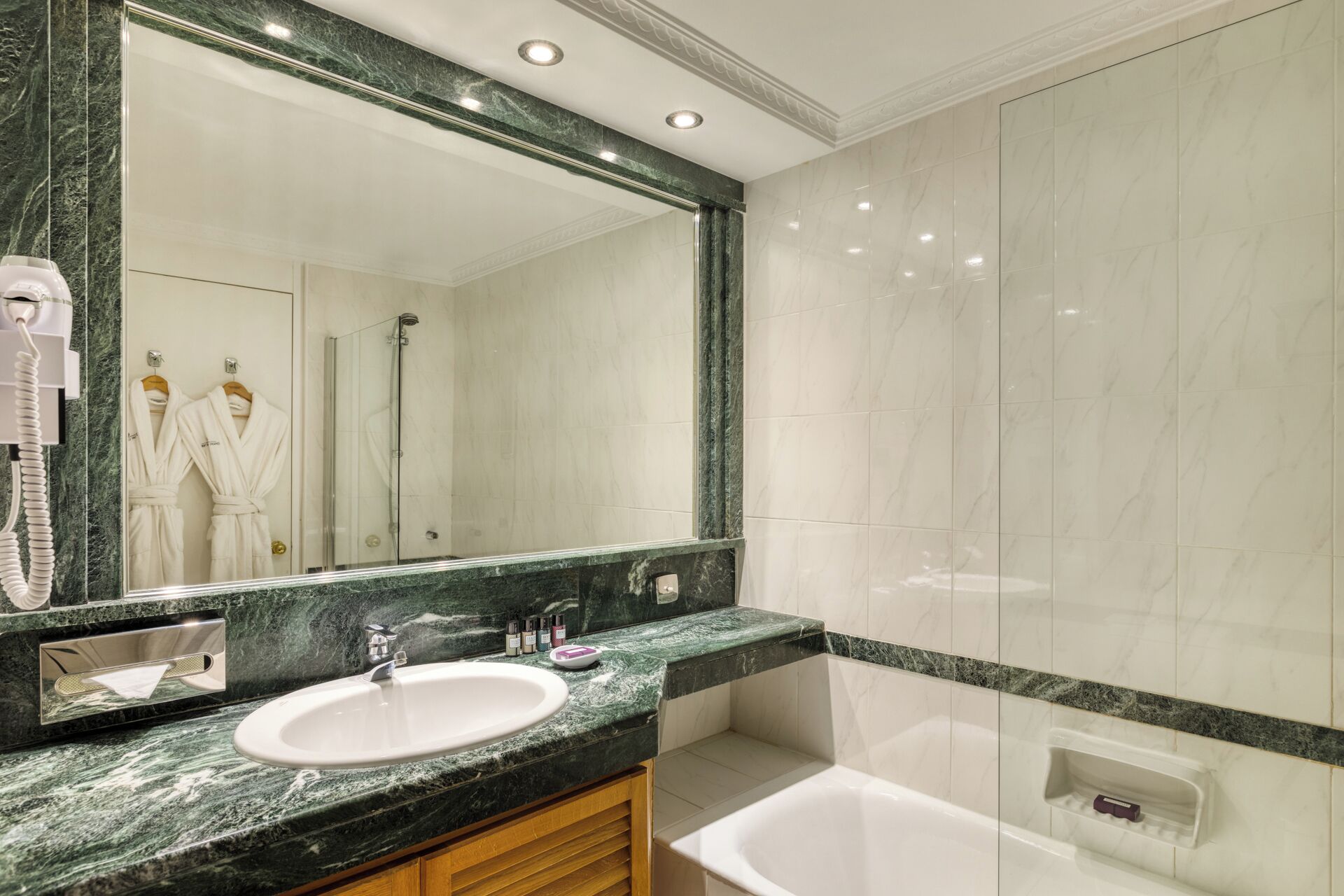 A bathroom with a large mirror, a sink, a bathtub, and a shower.