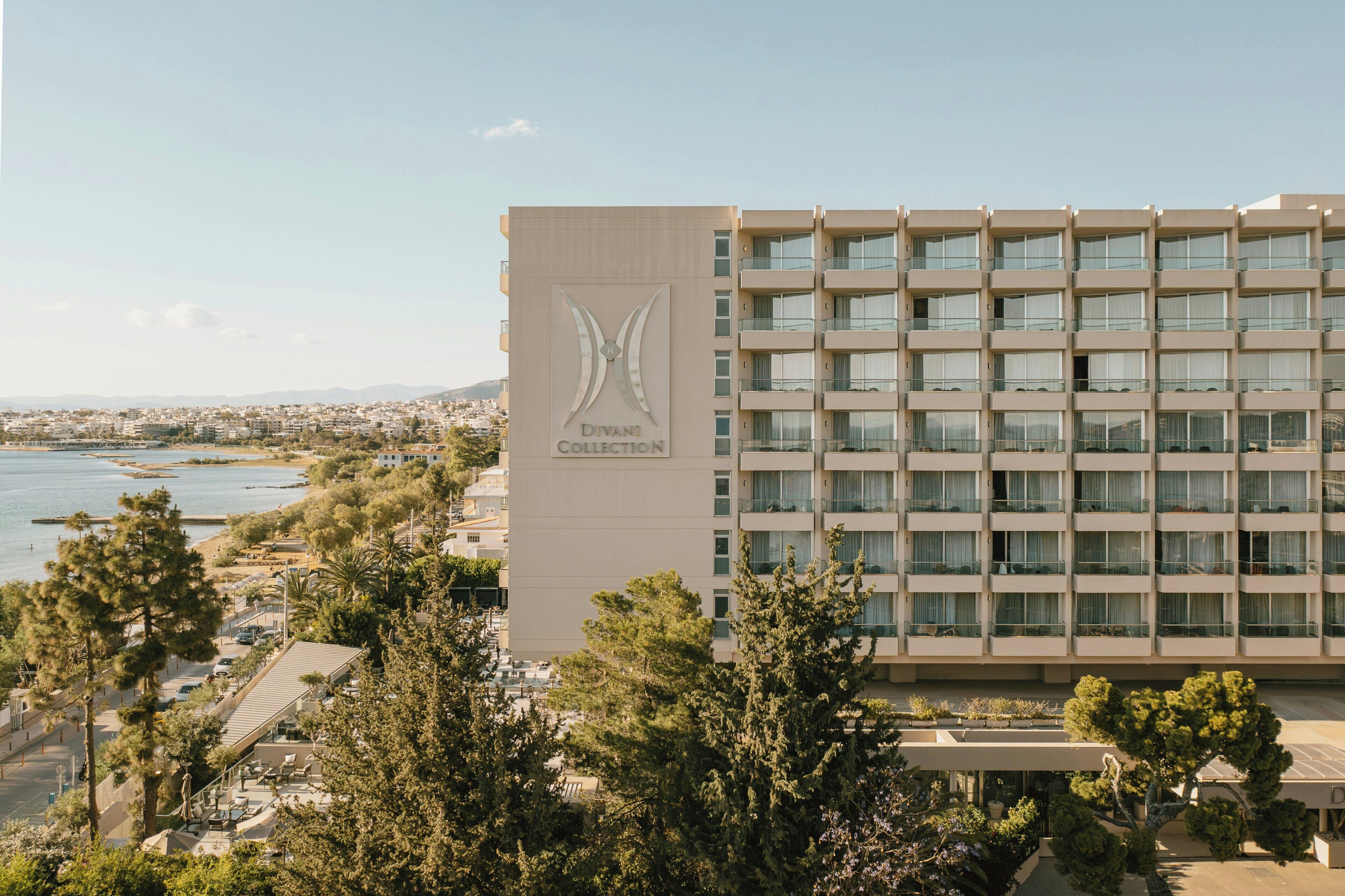A hotel building with a prominent logo on the facade, multiple balconies, and a view of the surrounding cityscape and water.