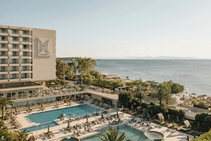 A hotel with a rooftop pool, outdoor seating, and a view of the sea.