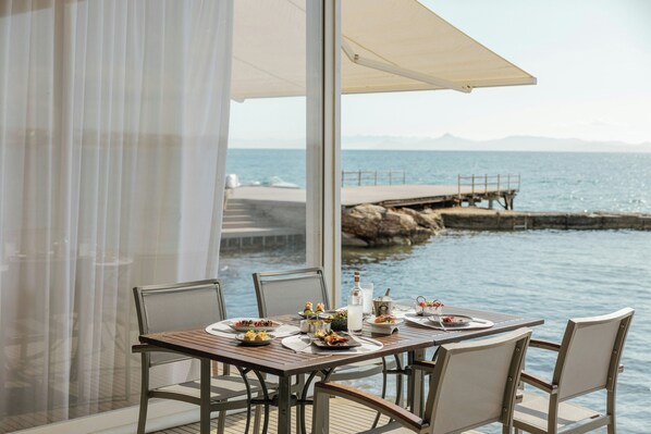 A table set for dining with a view of the sea and a pier in the background. - Divani Apollon Palace & Thalasso (Vari-Voula-Vouliagmeni)