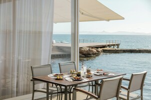 A table set for dining with a view of the sea and a pier in the background.