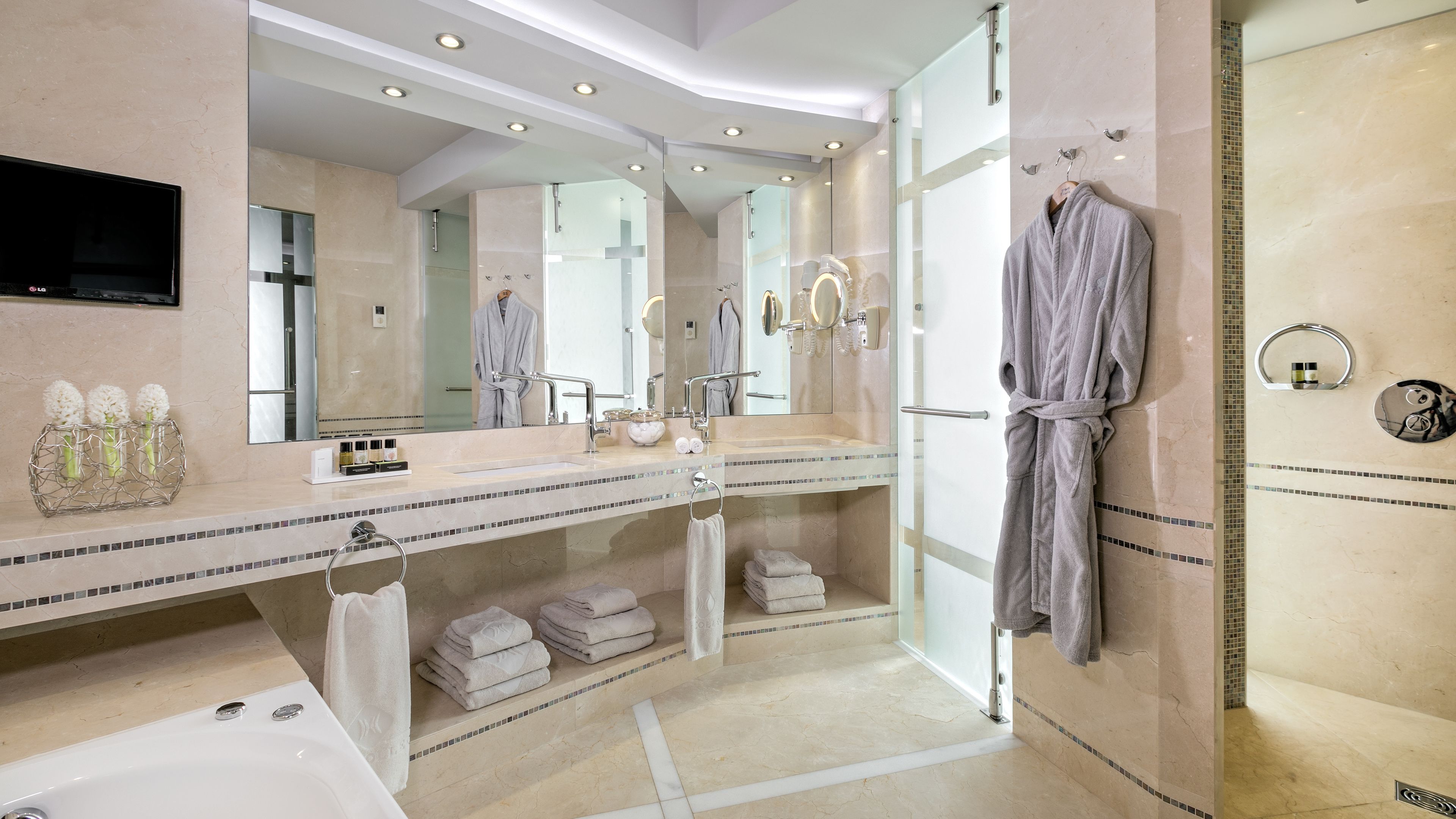 Un baño moderno con un espejo grande, dos lavamanos, una bañera y una ducha a ras de suelo.